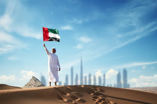 Uae bayrağını çölde tutan Arap adam Uae bayrağını ve Uae bayrağını kutluyor..