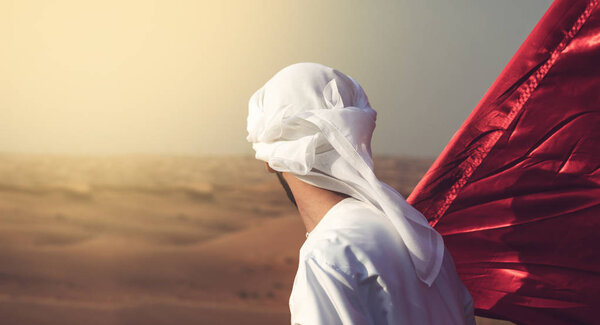 arab man holding flag walking alone in the desert