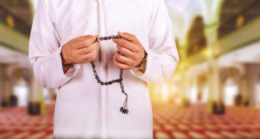 Arap Müslüman adam, camide Allah için dua ediyor. Günbatımında, Ramazan Kareem. Tasbih konsepti.