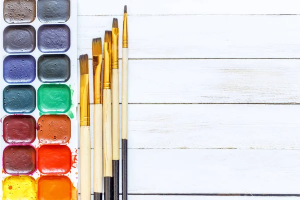Farben und Pinsel auf weißem Holzgrund — Stockfoto