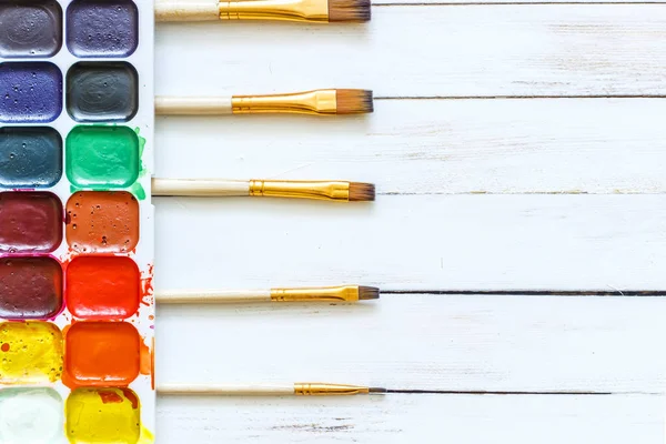 Farben und Pinsel auf weißem Holzgrund — Stockfoto