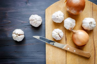 Soğan, sarımsak ve bıçak siyah ahşap zemin