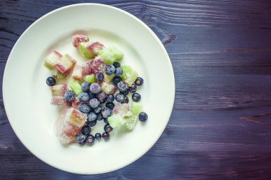Siyah frenk üzümü çilek ve beyaz tabakta ravent parçalarını donmuş. Yukarıdan görüntülemek.