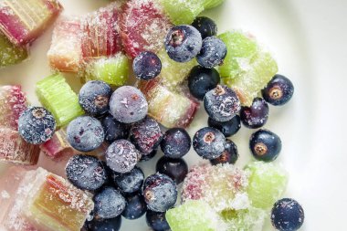 Siyah frenk üzümü çilek ve beyaz tabakta ravent parçalarını donmuş. Yukarıdan görüntülemek.