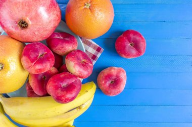 Kırmızı nektarin, muz, plaka ve mavi ahşap zemin üzerine nar