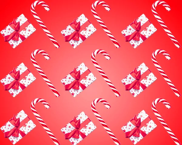 Pattern made from Christmas candy canes and gifts isolated on red background. Christmas holiday concept. Top view. Flat lay — Stock Photo, Image