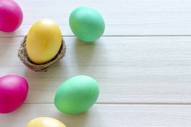 Paskalya yumurta beyaz ahşap zemin üzerinde pastel renklerde boyanmış.