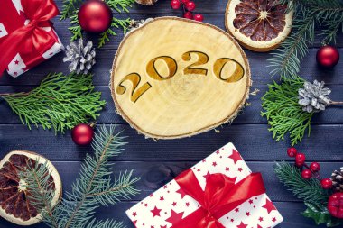 Noel ve yeni yıl arkaplanı süslemeler ve karanlık ahşap arka planda hediye kutuları. 2020 'de ahşap bir kesikte yanmış..
