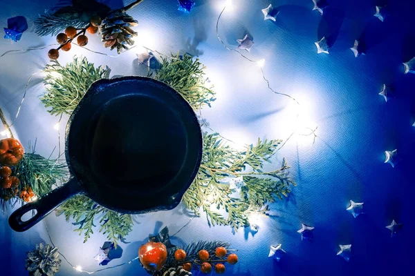 Christmas table setting with empty iron pan with christmas light and thuja branches . Winter holidays and festive background. Christmas eve dinner, New Year food lunch. Top view. — Stock Photo, Image