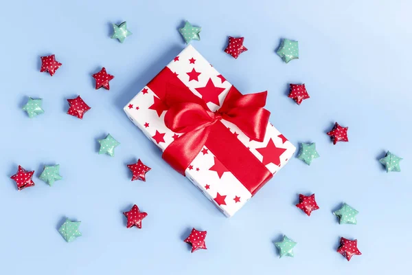 Cadeaudoosje verpakt in kraftpapier en veelkleurige sterren op blauwe achtergrond. Top uitzicht, vakantie concept. — Stockfoto