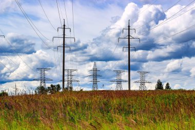 Gökyüzünde yüksek voltajlı elektrik direkleri ve bulutlar.