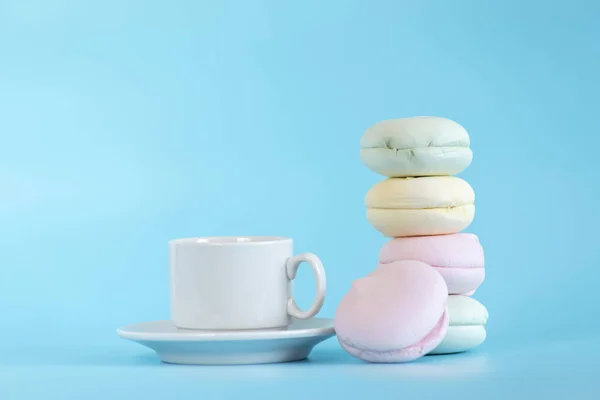 Air marshmallows in pastel shades with cup tea. A gentle marshmallows. A gentle zephyr on a blue background. Marshmallows in a light key