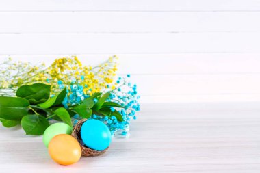 Beyaz ahşap bir masada sepetteki paskalya yumurtaları. Boşluğu kopyala