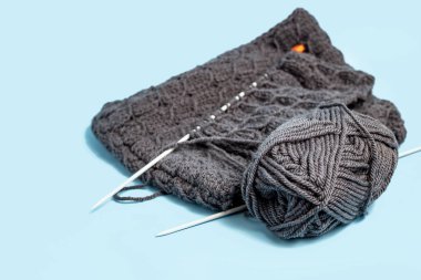 Yünden örgü örüyorum. Mavi arka planda örgü iğneleri ve yünler