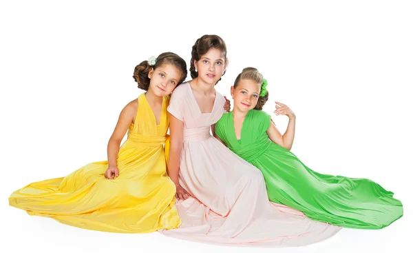 Tres chicas en vestidos de colores abrazando y mirando a la cámara — Foto de Stock