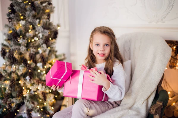 Image de belle fille avec des boîtes-cadeaux assis sur un fauteuil à la maison. Décoré arbre de Noël fond — Photo