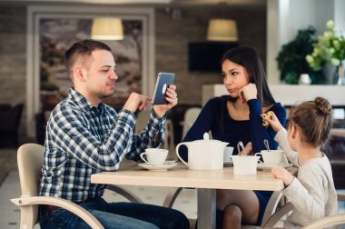 Modern aile değerleri. Elektronik cihazlar tablet pc, karısı ve kızı mutsuz bir kafede oturan kullanma hakkında bağımlısı baba