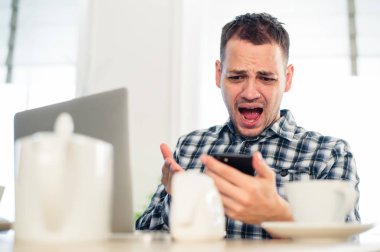 Kötü haber. Kızgın genç adam bir cep telefonu tutarak ve café'de yapması