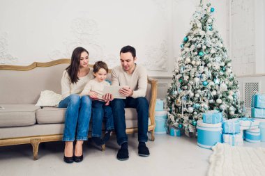 Neşeli aile Noel Baba onu dekore edilmiş Noel ağacın arkasında getirdi dijital tablet ile eğleniyor oturma odasında oturmuş