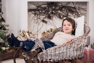 Bir kızak üzerinde Noel süslemeleri küçük bebek oturuyor.