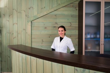 Receptrion kadın gülümsüyor ve spa ya da modern klinik sanal ziyaretçi ağırlıyor. Anlaşma senin elinde kağıtlarla.