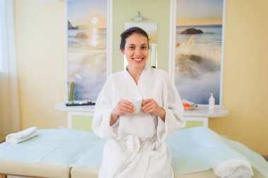 Bir bornoz giymiş ve bazı çay içerek yorgunluk spa onu sırayla için bekleyen genç ve güzel İspanyol kadın