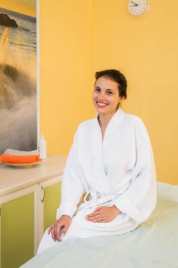 Bir Spa Masaj için bekliyor beyaz havlu kumaş bornoz giymiş güzel genç kadın.