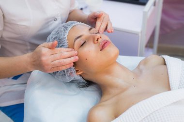 Kaplıcada yüz bakımı yapan genç bir kadın.