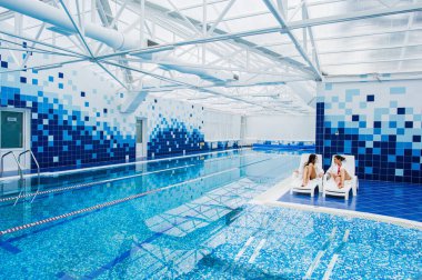 İki genç kadın rahatlatıcı tarafından sarılma elbiseler giyen ve havuz kenarı