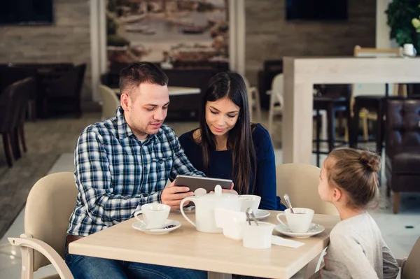 Aile, ebeveynlik, teknoloji insanlar kavramı - mutlu anne, baba ve küçük kız ile tablet pc bilgisayar restoranda akşam yemeği