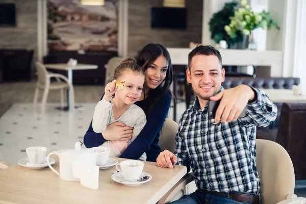 家庭，生儿育女，技术人概念 — — 快乐的妈妈，爸爸和小女孩自拍照以智能手机的餐厅吃饭 — 图库照片