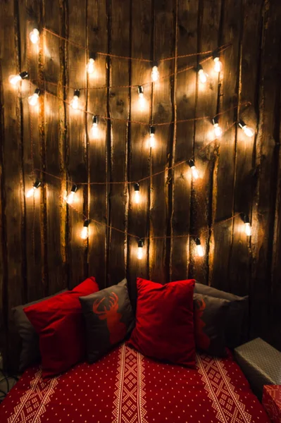 Sala de madeira em casa rústica com parede e designer lâmpadas, lugar decorado para assento. Travesseiros cinza vermelho . — Fotografia de Stock