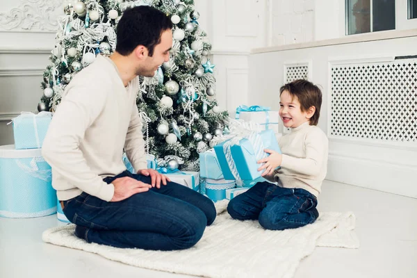 Padre e hijo desenvolviendo un regalo tirado en el suelo —  Fotos de Stock