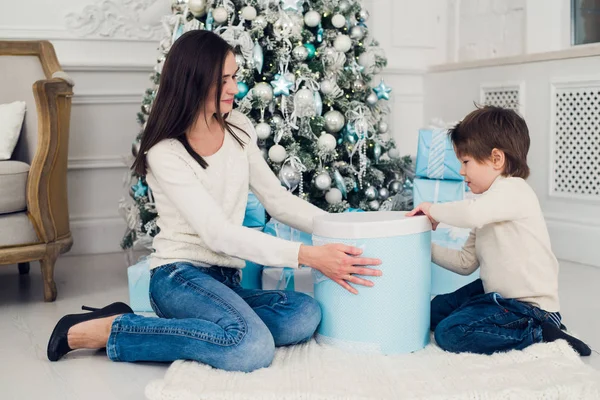 Gelukkig moeder met een jongetje in de buurt van de kerstboom. Nieuwjaars geschenken — Stockfoto