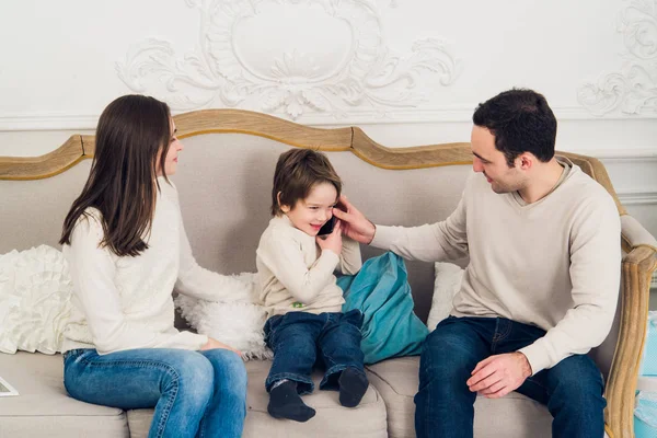 Family phone talking - cute little boy, his mother and father are sitting on the sofa — Stock Photo, Image