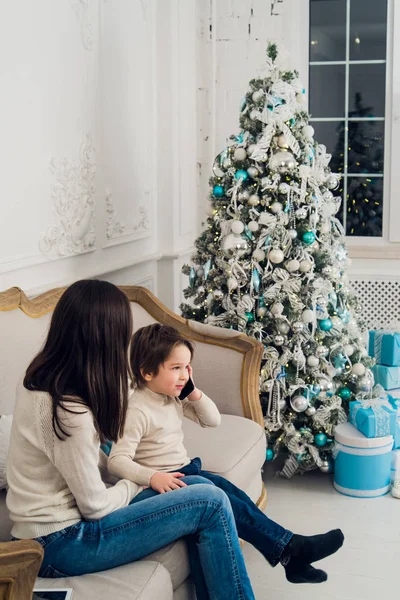 Familie telefoon praten - schattige kleine jongen, zijn moeder zitten op de Bank — Stockfoto