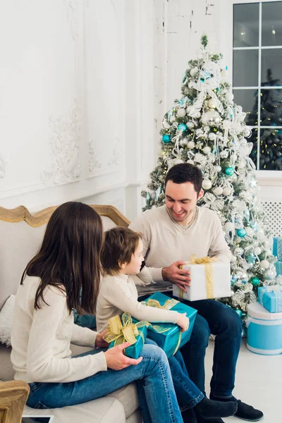 Felicidad, generación, vacaciones y concepto de personas - familia feliz con cajas de regalo sentado en el sofá en casa —  Fotos de Stock
