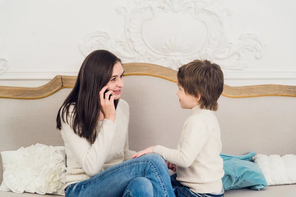 Family phone talking - cute little boy, his mother are sitting on the sofa — Stock Photo, Image