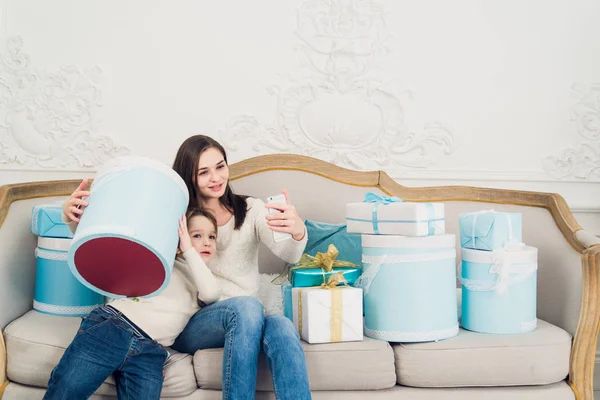 Jonge gelukkige familie moeder en zoon nemen van een foto van zichzelf met de giften van Kerstmis op sofa in de woonkamer — Stockfoto