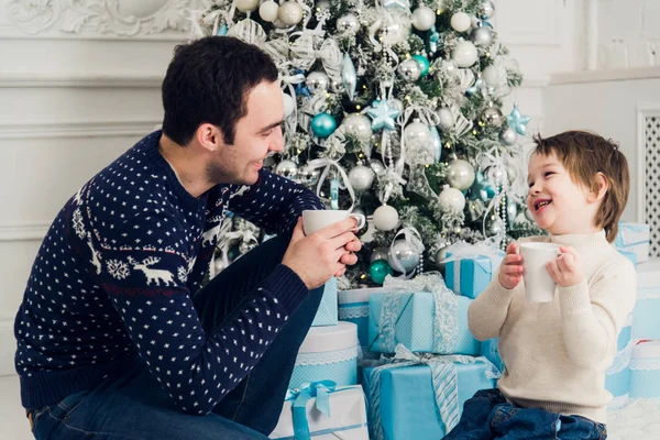 Feliz pai e filho com xícaras de chá falando perto da hora de Natal em casa — Fotografia de Stock