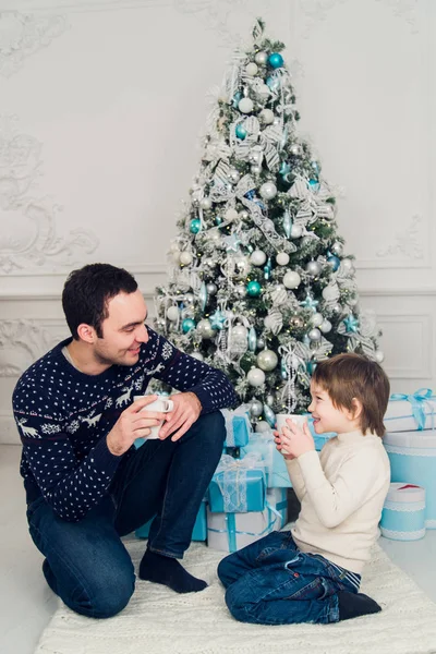 Vader met zijn zoon zittend ontspannen in ski resort chalet en het drinken van hete thee, vreugdevolle wintervakantie, mensen reizen op kerstvakantie — Stockfoto