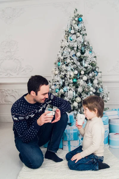 Pai com seu filho sentado relaxado em chalé estância de esqui e beber chá quente, férias de inverno alegres, pessoas que viajam nas férias de Natal — Fotografia de Stock