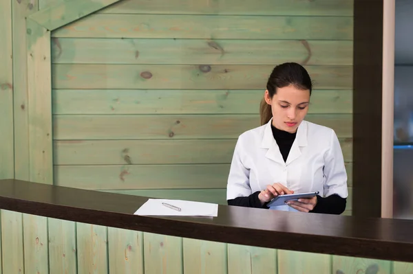 Vrouw in een spa recpetion gebruikt tablet pc texting aan de client. Schoonheid en technologie concept. — Stockfoto