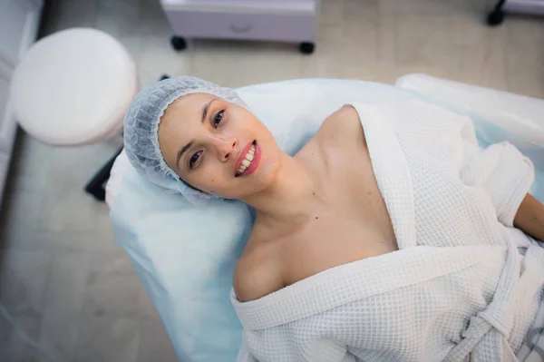 Vedere de sus a femeii tinere frumoase care se pregătește pentru tratamentul pielii feței, întinsă pe pat la spital sau clinică — Fotografie, imagine de stoc