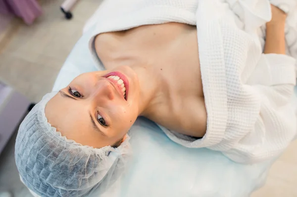 Pohled shora z krásné mladé ženy připravuje na ošetření pleti obličeje, ležící na posteli v nemocnici nebo na klinice — Stock fotografie