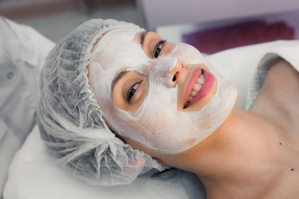 Young woman at spa procedures applying mask