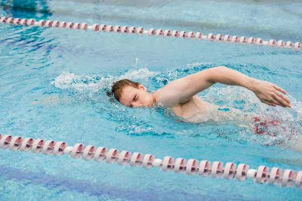 Uomo nuota utilizzando il tratto strisciante in piscina coperta — Foto Stock