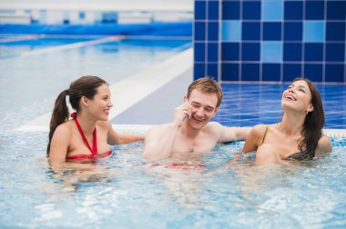 Yüzme Havuzu yapım çağrı cep telefonunda gülümseyen insanlarla. Sağlık, gevşeme ve iletişim kavramı