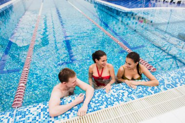 Genç yetişkinler eğleniyor kapalı yüzme havuzunda konuşuyor