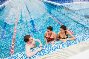 Genç yetişkinler eğleniyor kapalı yüzme havuzunda konuşuyor